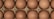 A close-up view of a dozen brown eggs arranged in a carton, showcasing their smooth, speckled surfaces nestled in a grid pattern.