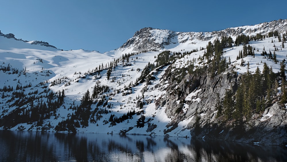 a mountain covered in snow next to a lake