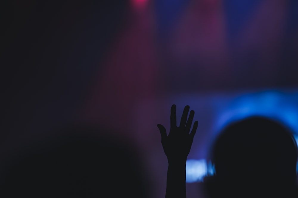 a silhouette of a person raising their hands in front of a stage