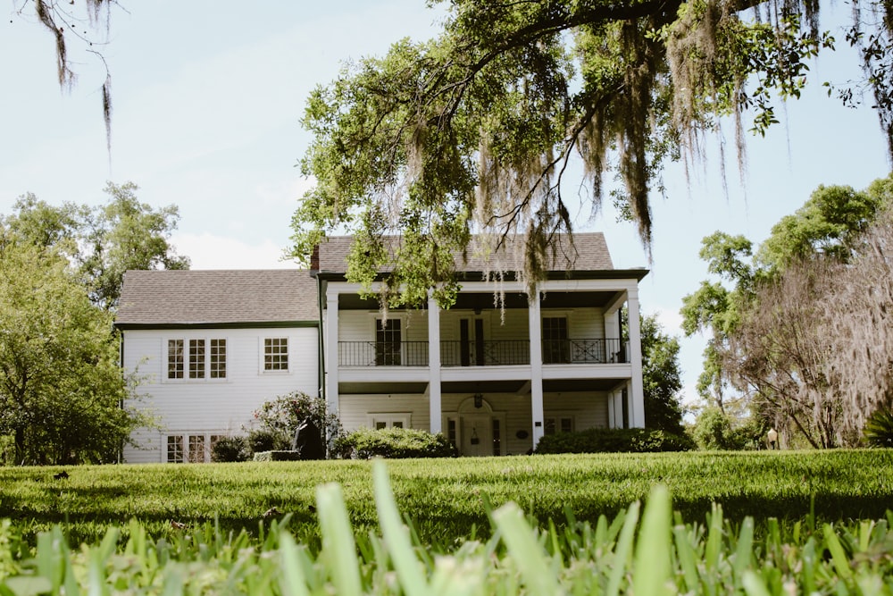 a large white house sitting on top of a lush green field