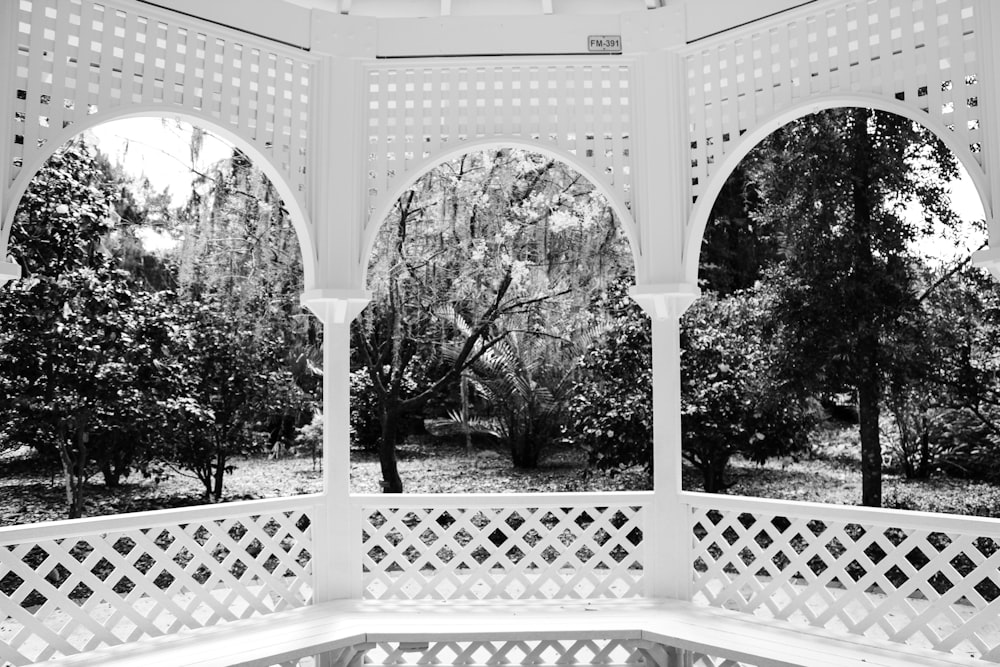 a white gazebo in a park with trees in the background