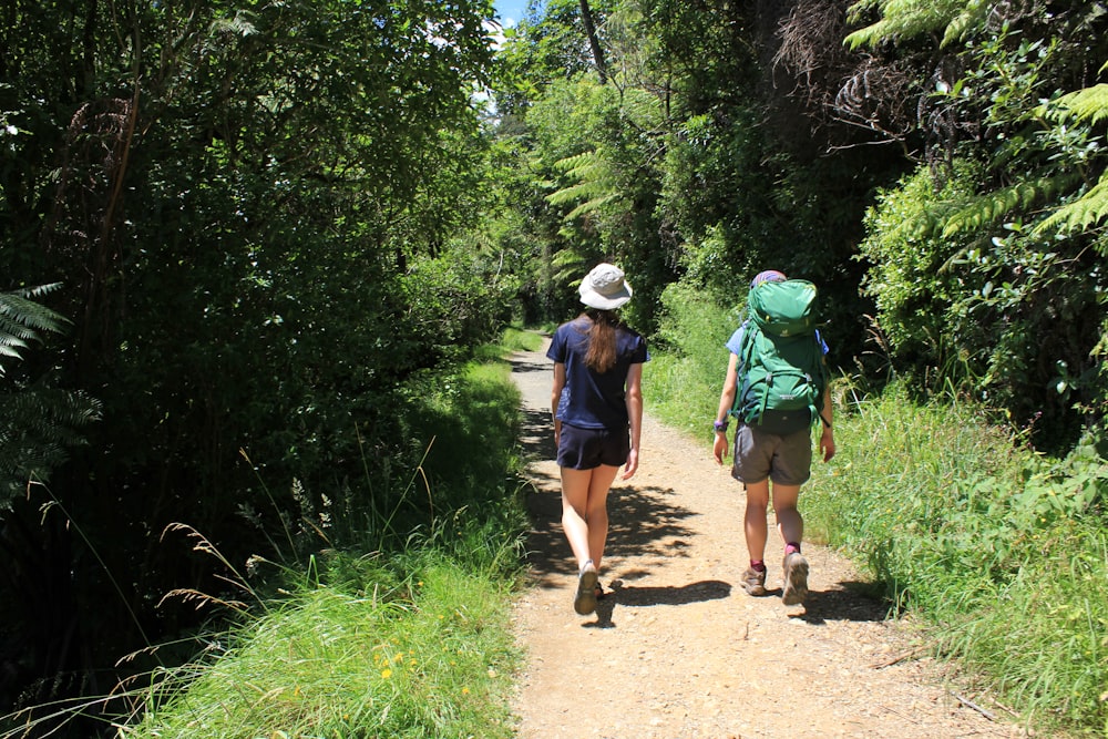 a couple of people walking down a dirt road