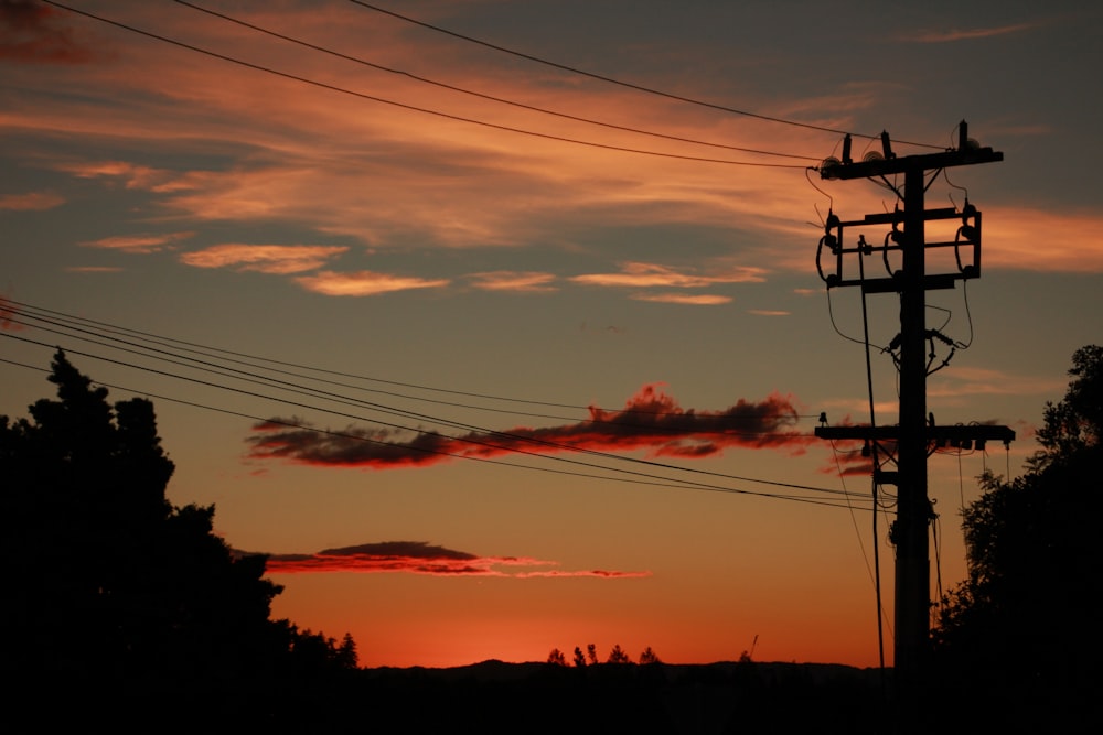 the sun is setting behind power lines and telephone poles