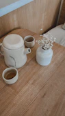 Cozy tea ritual scene featuring a cream-colored teapot and two cups on a minimalist wooden tray.