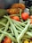 A collection of fresh vegetables including ripe tomatoes, green beans, papayas, and cucumbers arranged together.