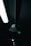 A darkly lit scene featuring a ceiling-mounted light fixture and a sensor device. The light fixture emits a soft white glow, while the sensor has a small green light. The background is mostly in shadow, adding a sense of depth and mystery.