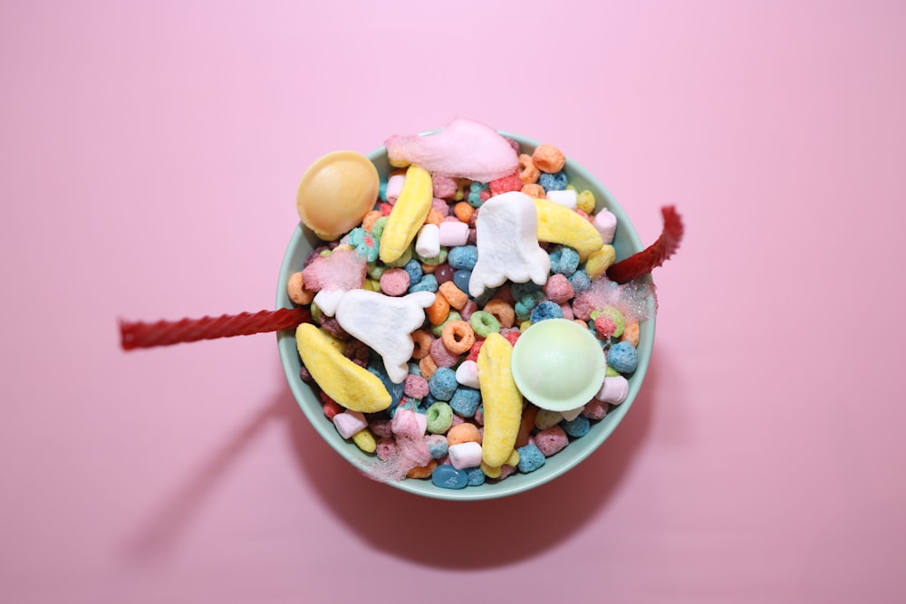a bowl filled with cereal and marshmallows on a pink background