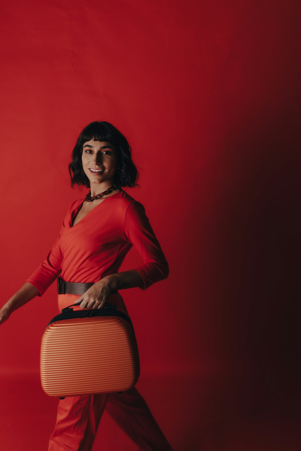 a woman in a red top is holding a suitcase