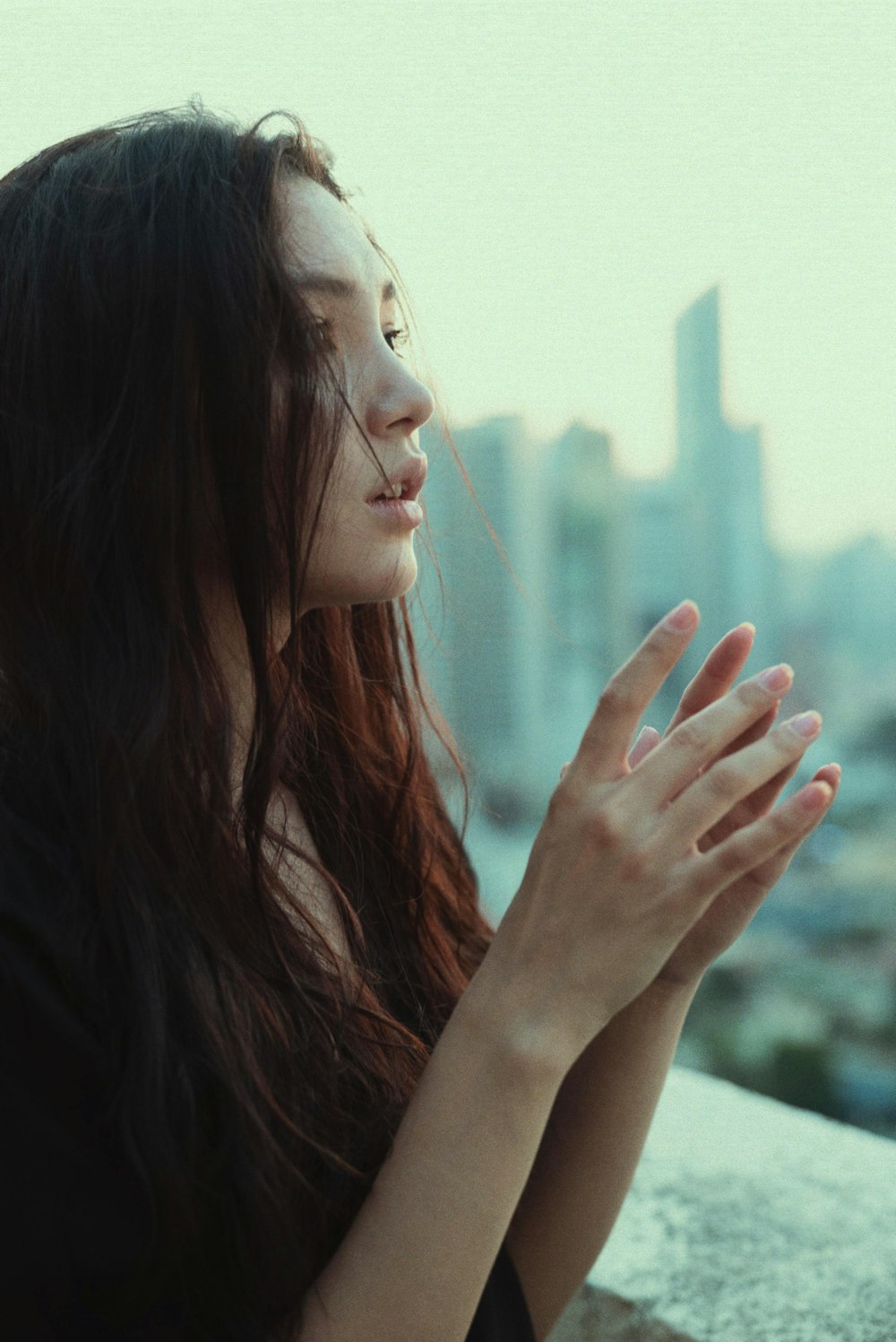 a woman holding her hands together with a city in the background