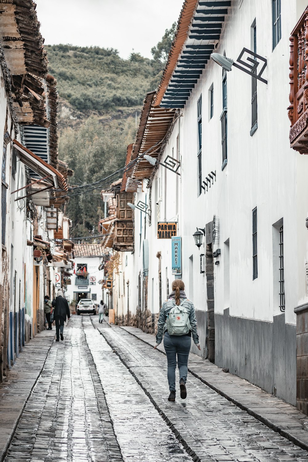 Una mujer caminando por una calle junto a edificios altos