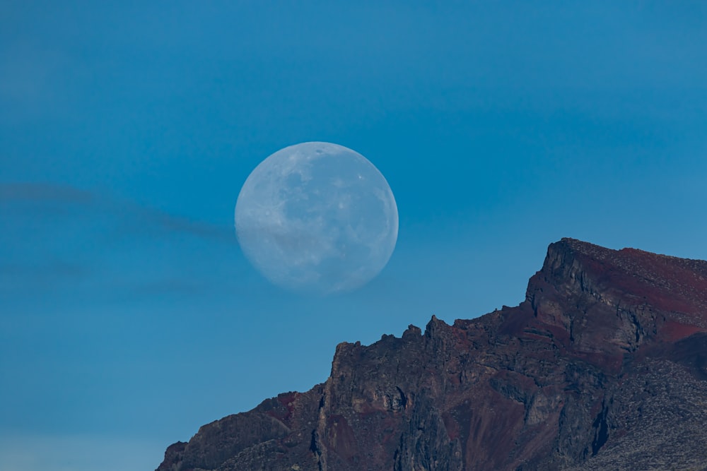 a full moon rising over a mountain range