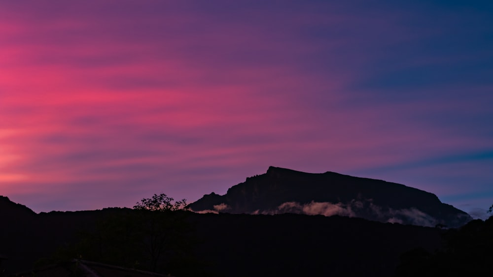 a pink and blue sky with a mountain in the background