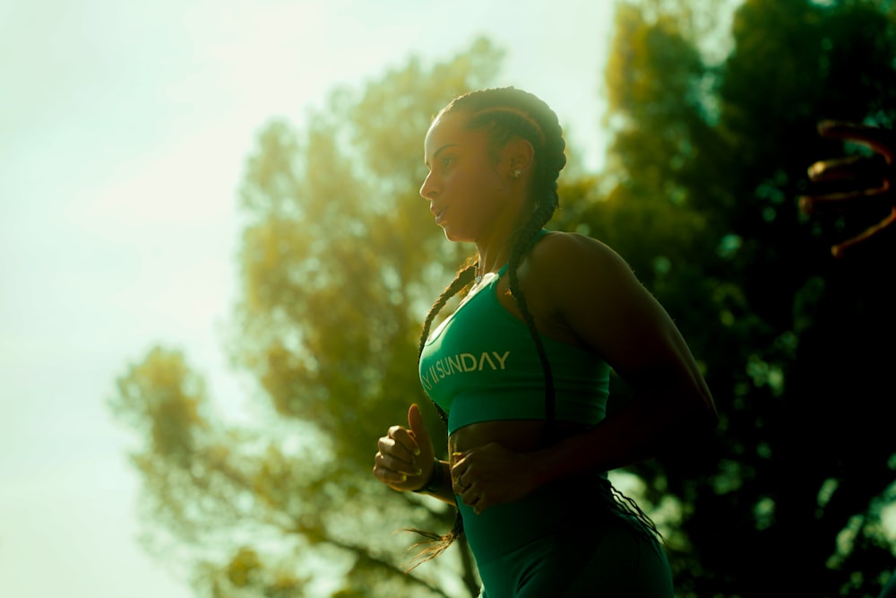 a woman in a green top running in the sun