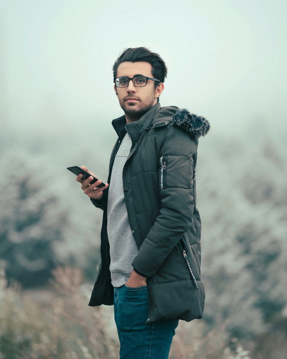 a man standing in a field looking at his cell phone