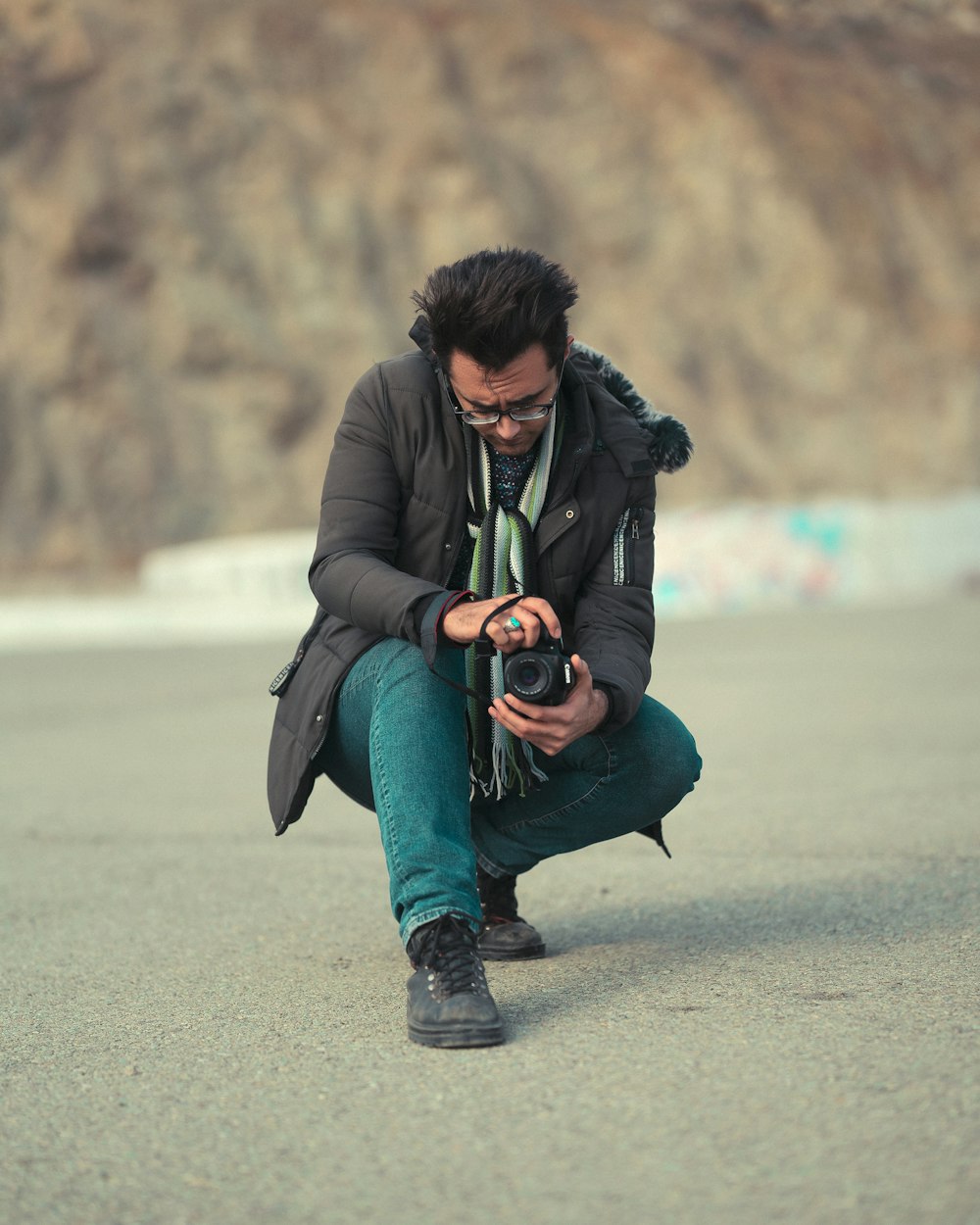 a man squatting down while holding a camera