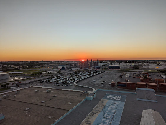 A panoramic view of a modern warehouse facility with trucks loading goods under a vibrant sunset sky.
