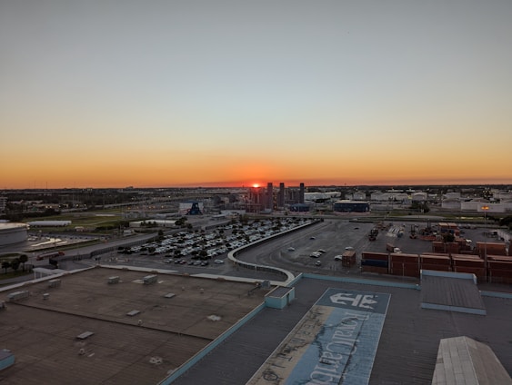 A panoramic view of a Gulf Coast refinery and tank farm at sunset with navy and gold hues.