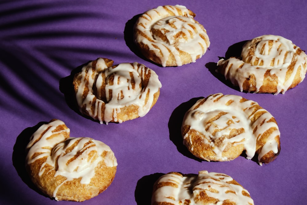 Un manojo de rosquillas con glaseado sobre una superficie púrpura