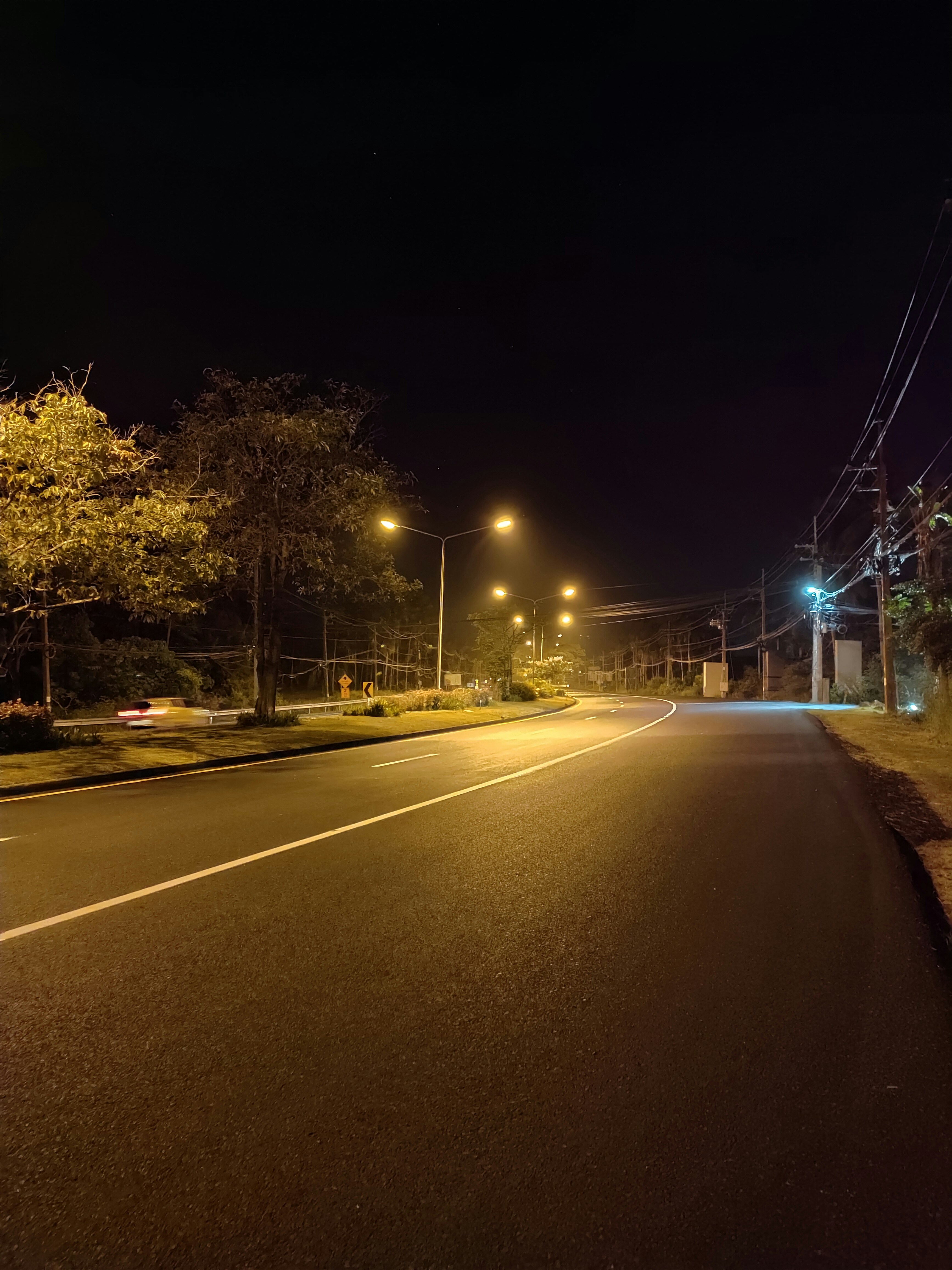 LED street lights on poles illuminating dark road at night