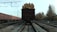 A loaded freight train car is seen on tracks, filled with cut logs stacked neatly at the back. To the left, a line of red cargo train cars is visible. The setting is an industrial railway area with overhead power lines and tracks extending into the distance. Autumn trees line the tracks, suggesting a late season setting.