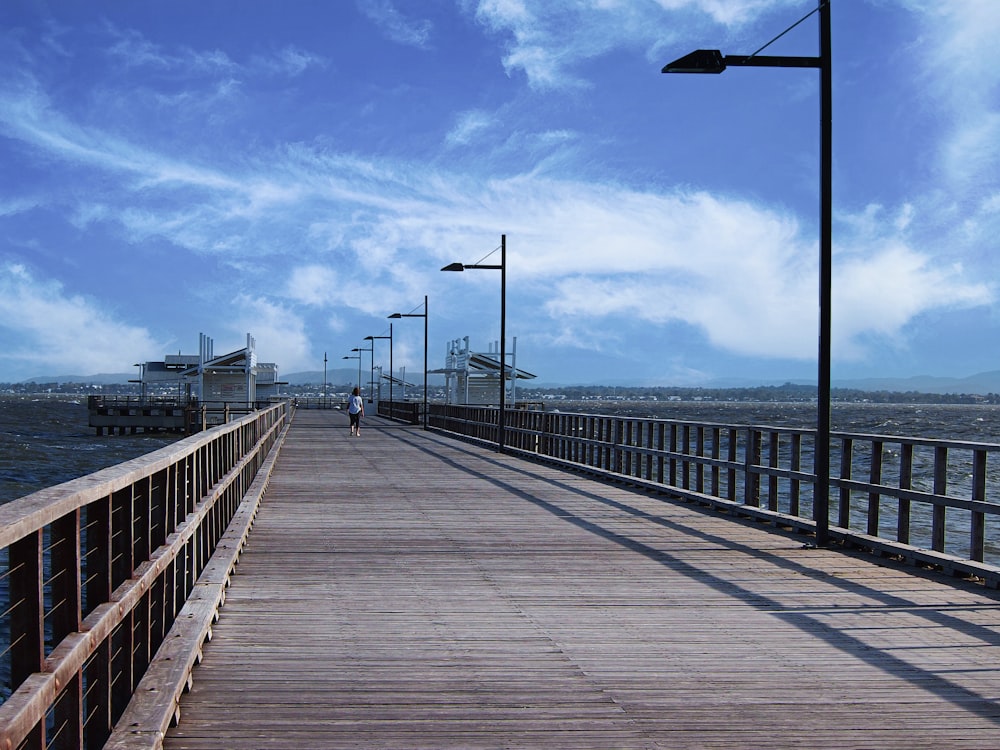 a person walking across a wooden bridge over a body of water