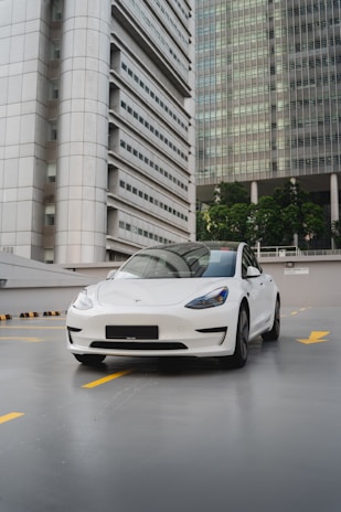 a white car parked in front of a tall building