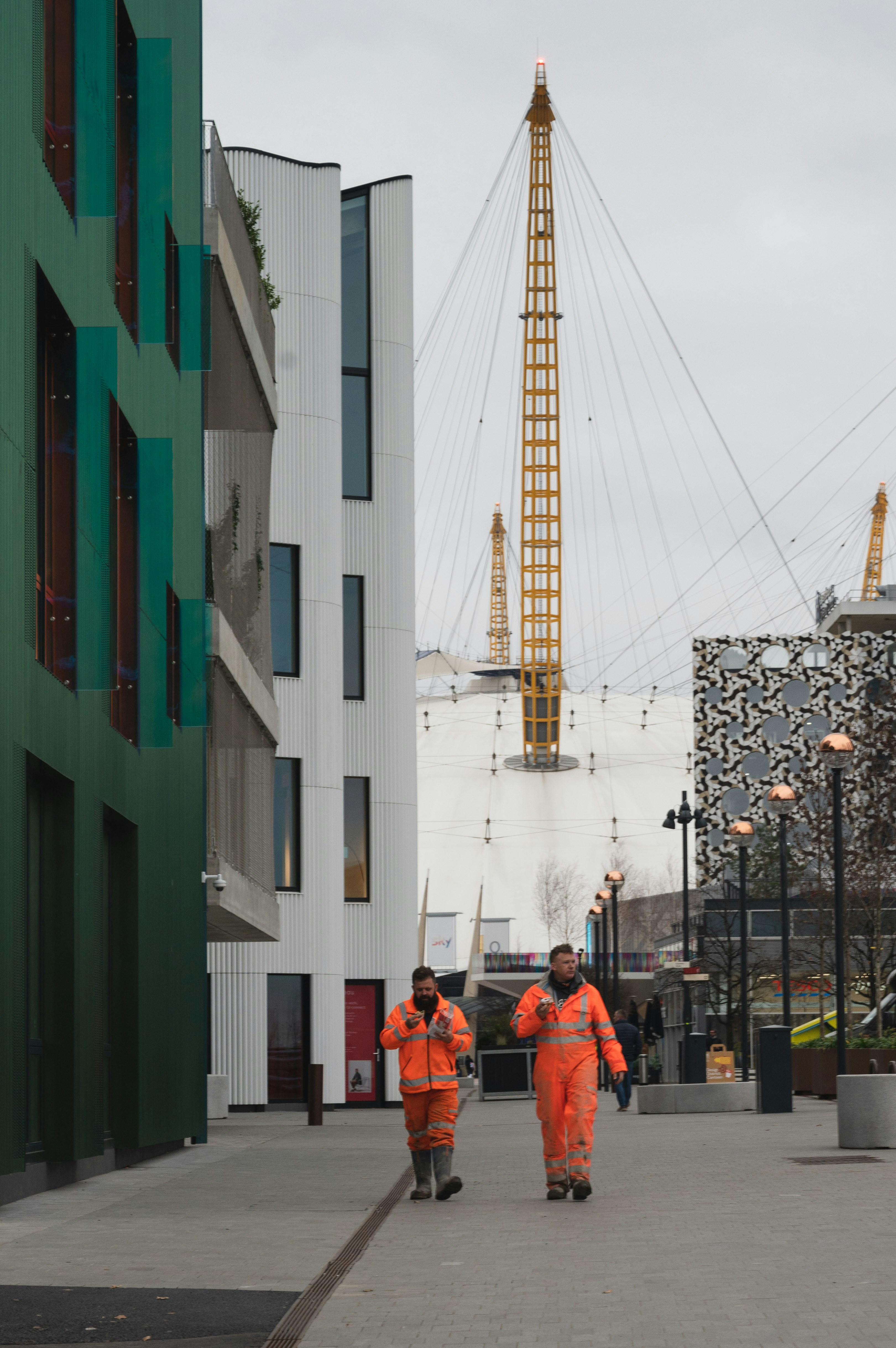 Una coppia di uomini in giacca arancione che cammina lungo una strada