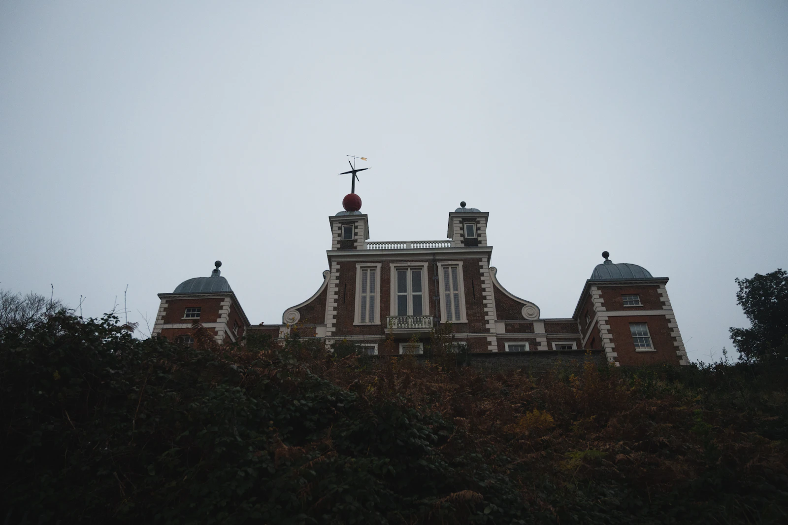 Photograph of A historic Royal Observatory building above the lawns and trees of Greenwich Park.