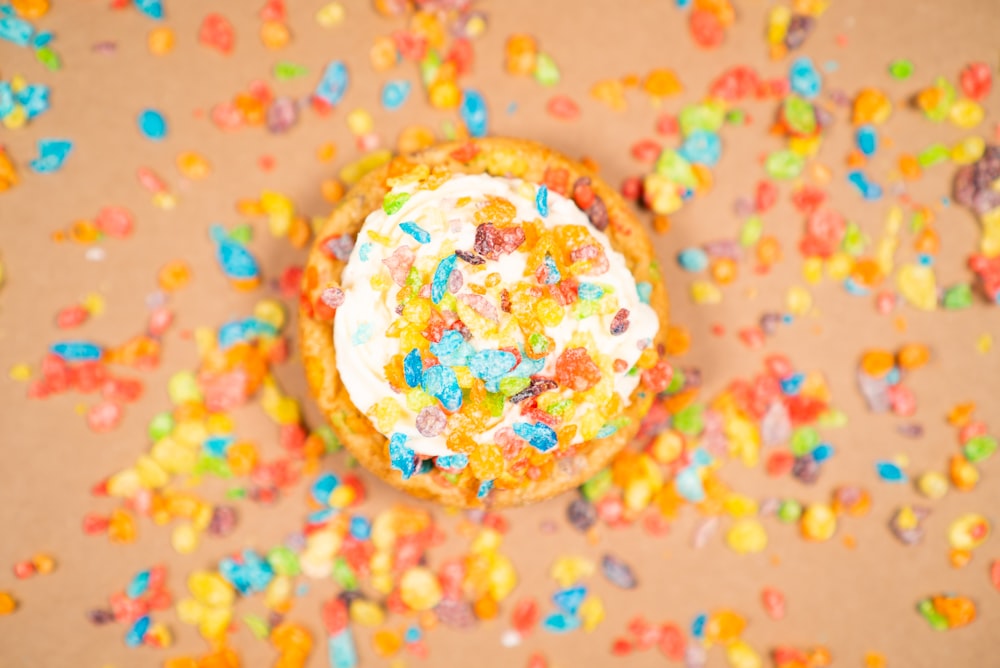 a cookie with white frosting surrounded by sprinkles