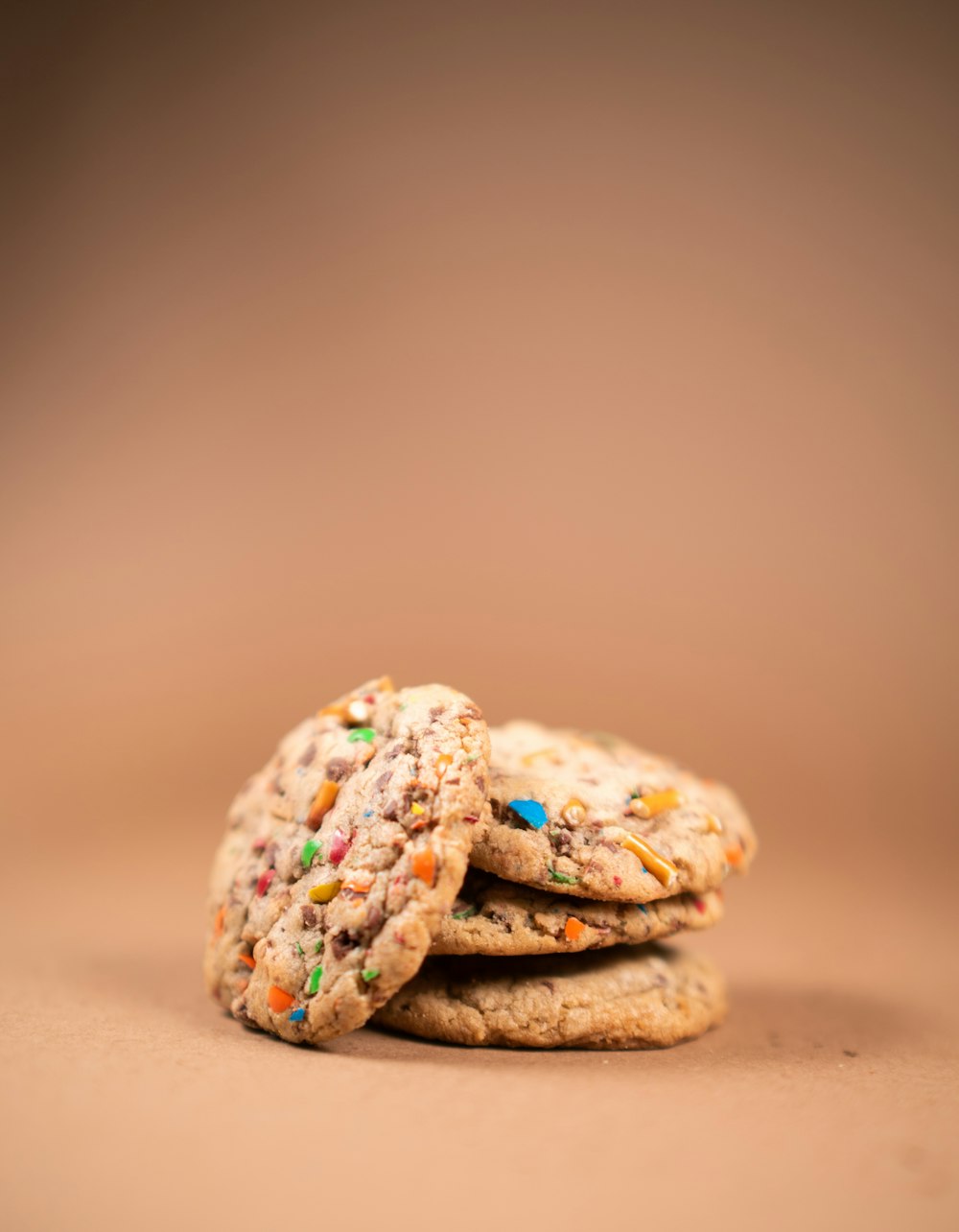 a stack of cookies with sprinkles on a brown background
