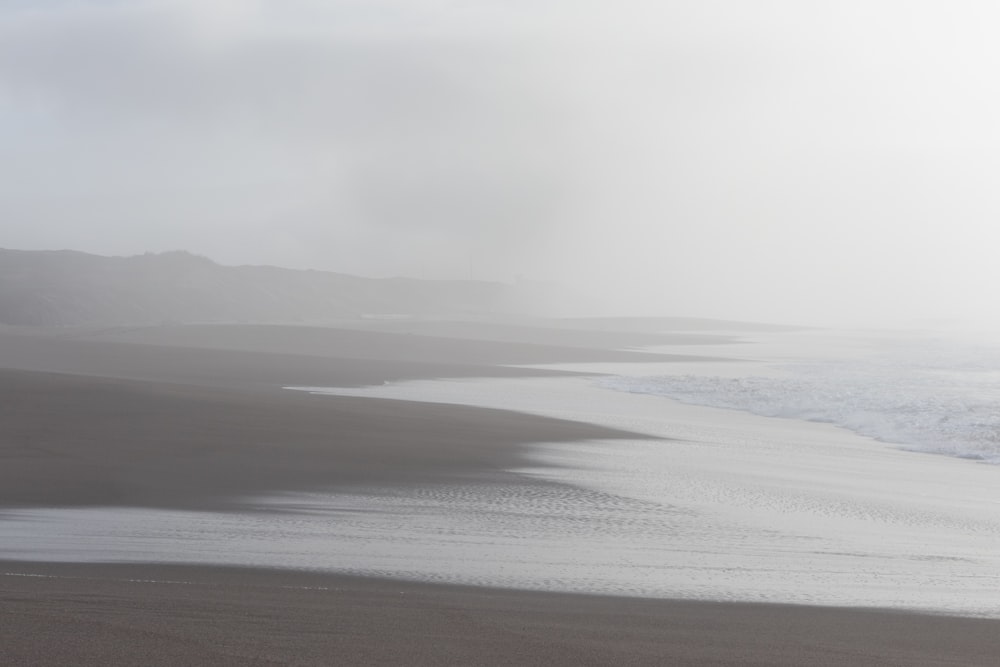 a foggy day at the beach with a person walking on the sand