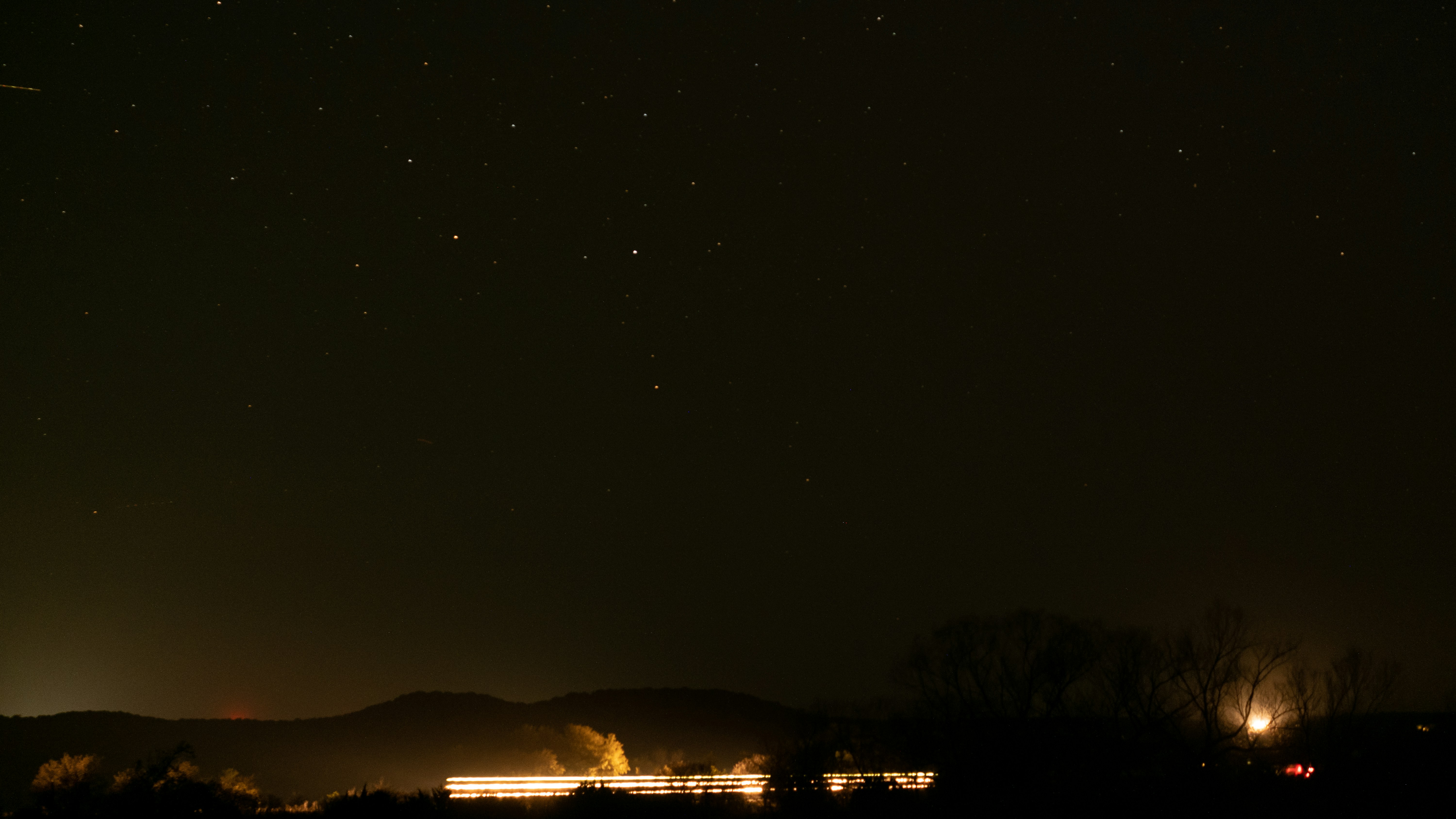a night sky with stars and a train on the tracks