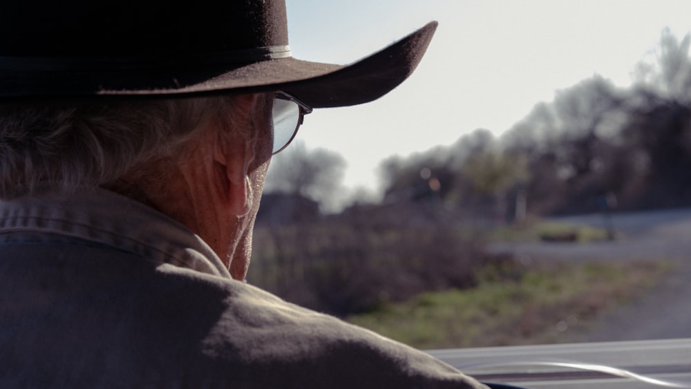 a man in a hat and glasses driving a car