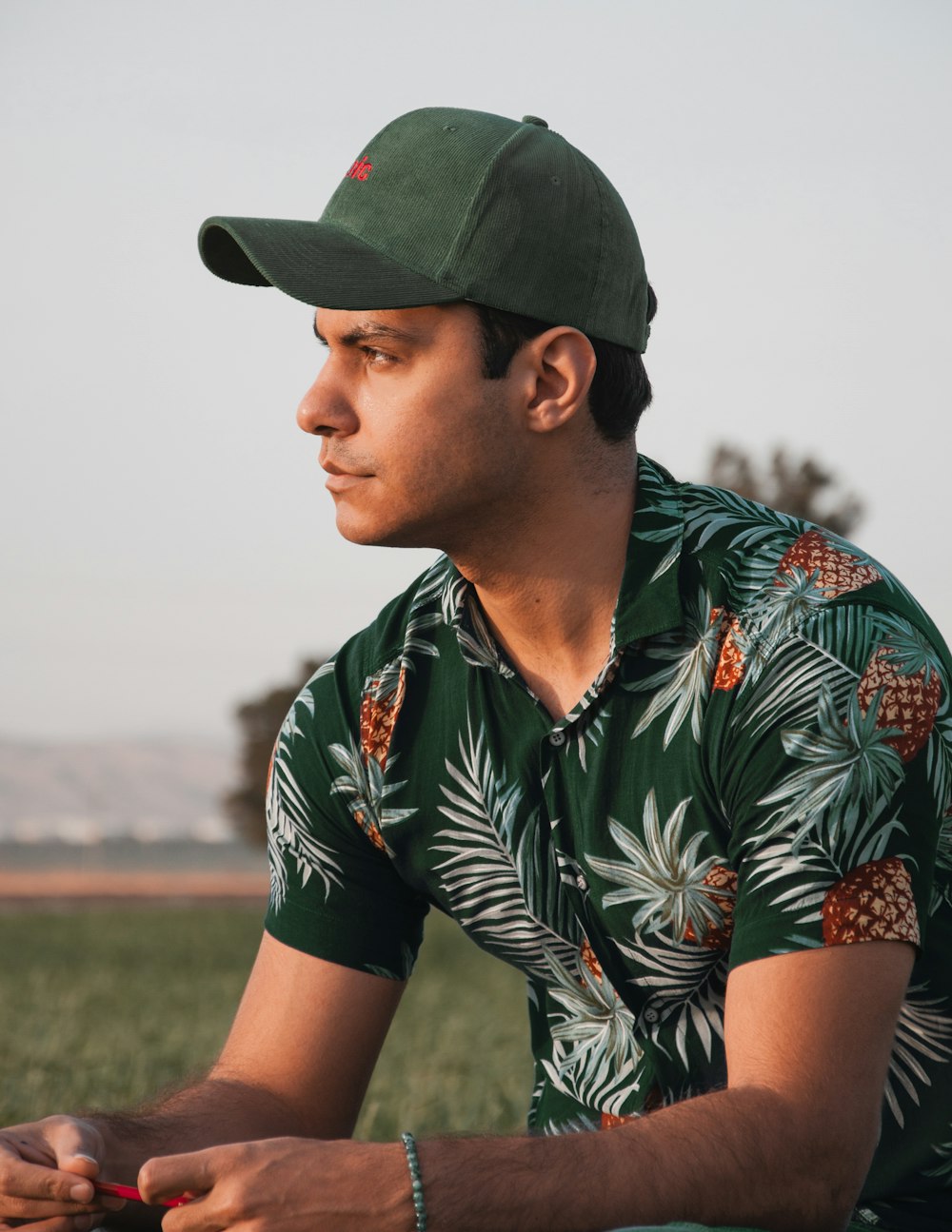 a man sitting in a field wearing a green hat