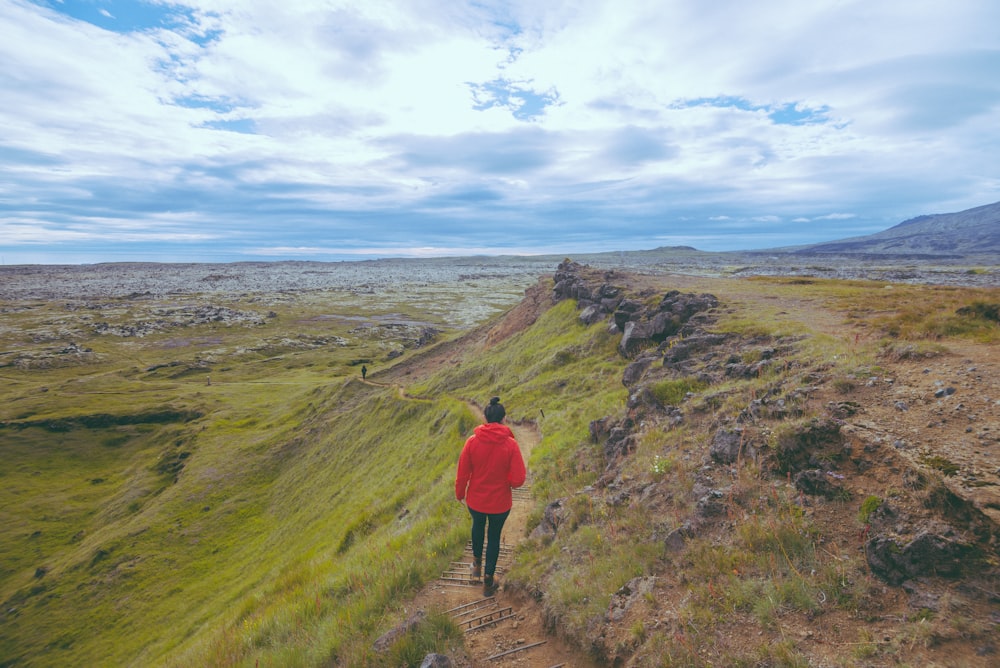 a person in a red jacket walking up a hill