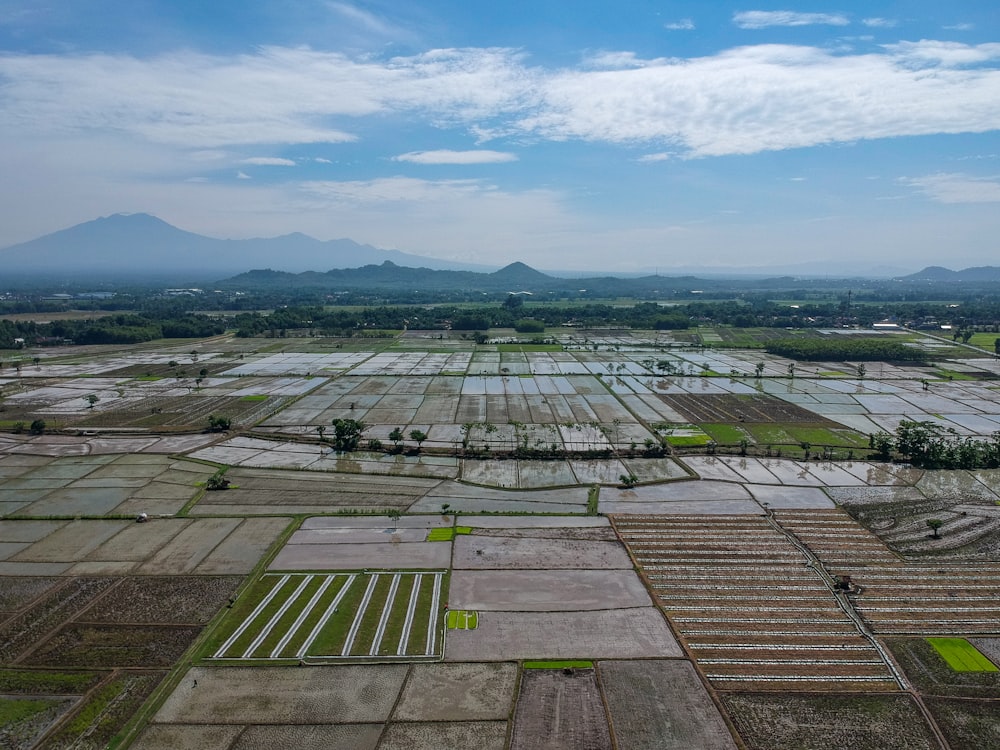 an aerial view of a farm land with mountains in the background