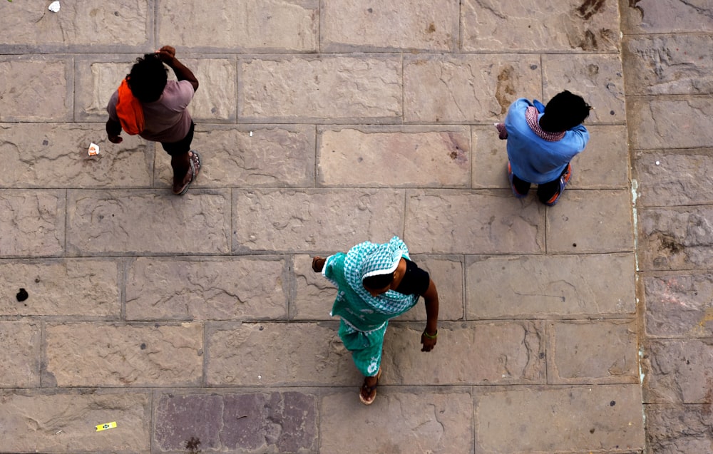 a group of people walking down a street next to a stone wall