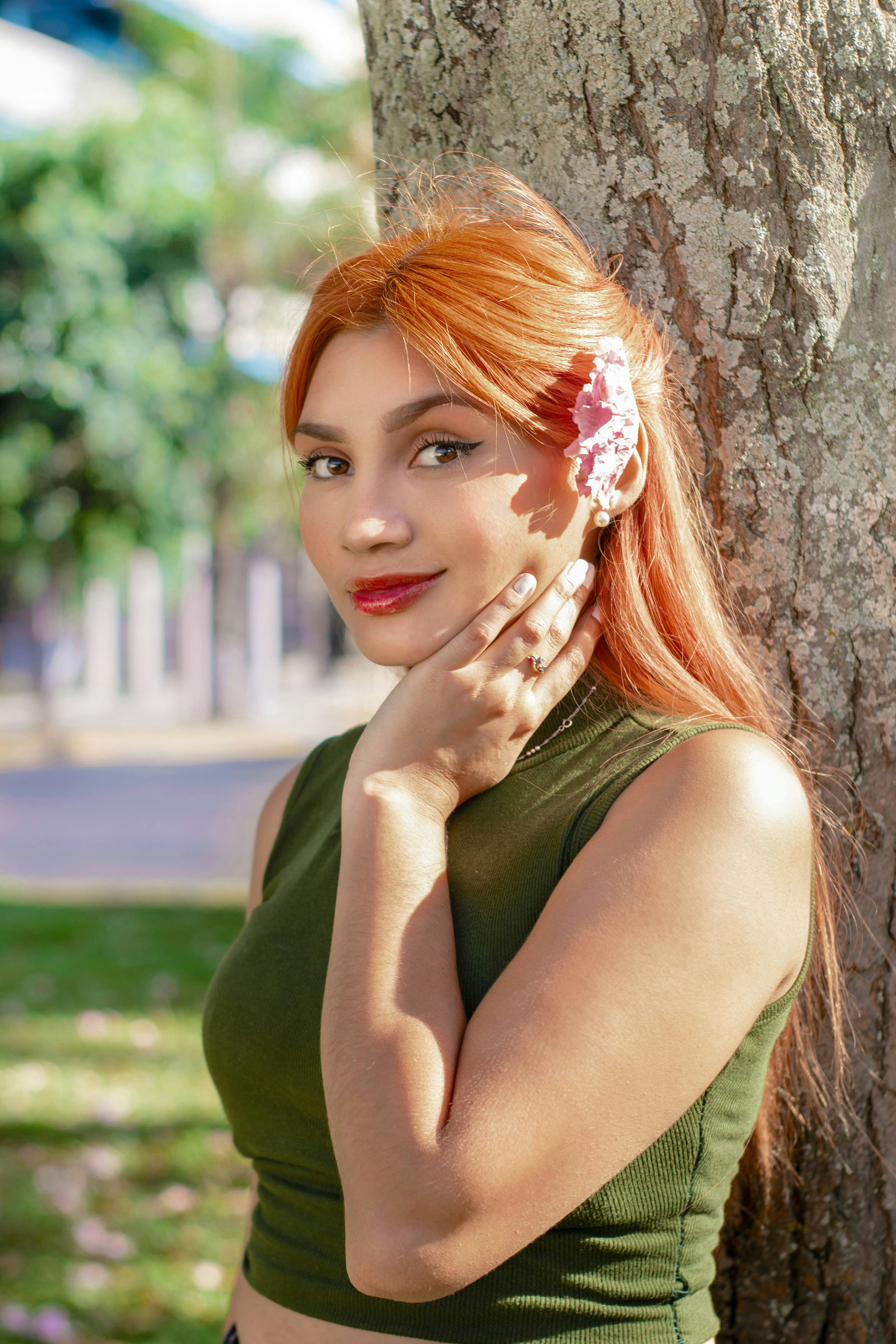 Eine Frau mit einer Blume im Haar, die sich an einen Baum lehnt