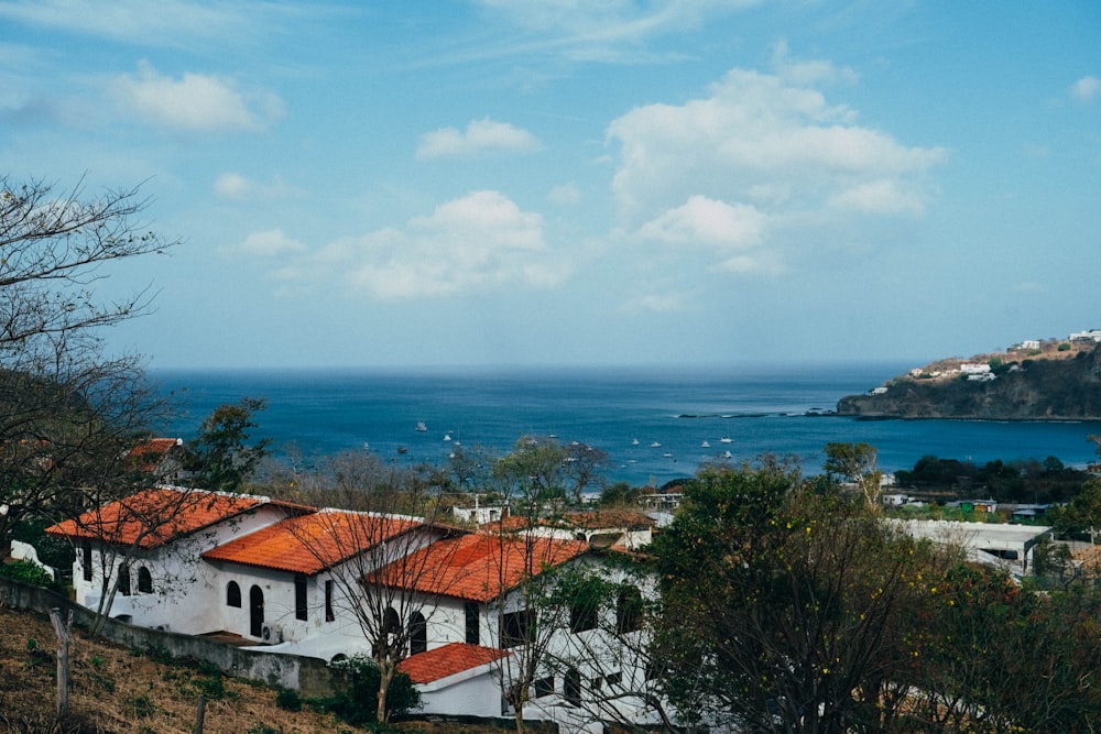 a white house with a red roof on a hill overlooking the ocean