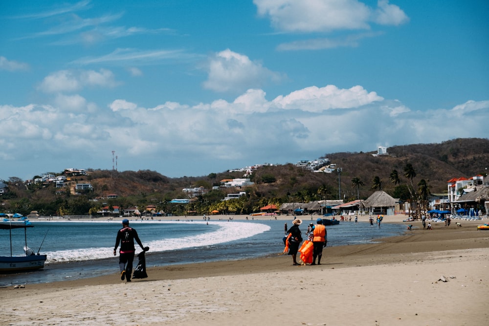 a group of people walking along a beach next to the ocean