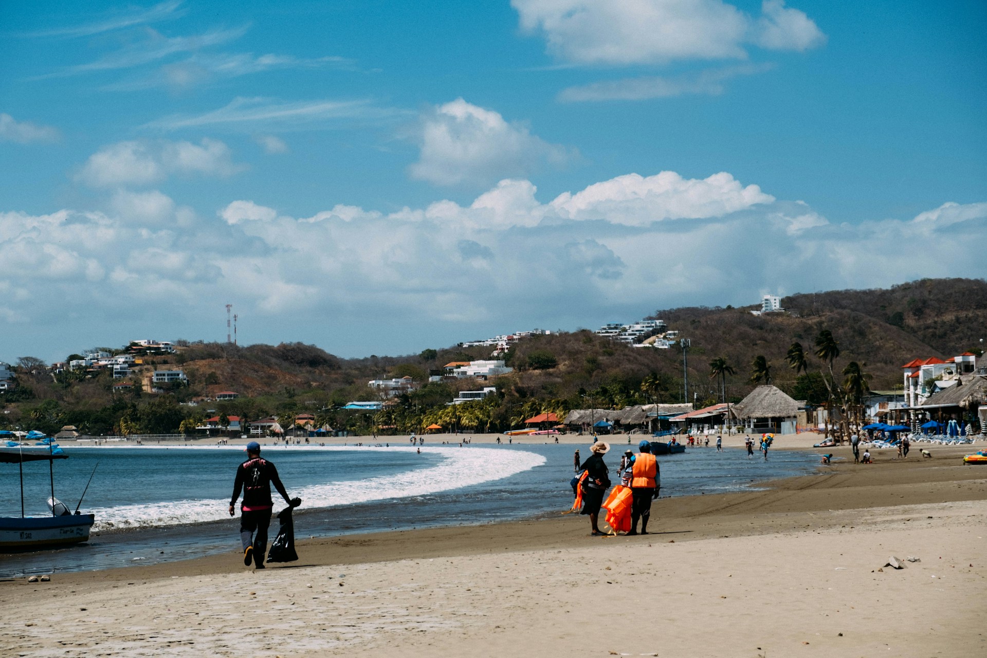 a group of people walking along a beach next to the ocean