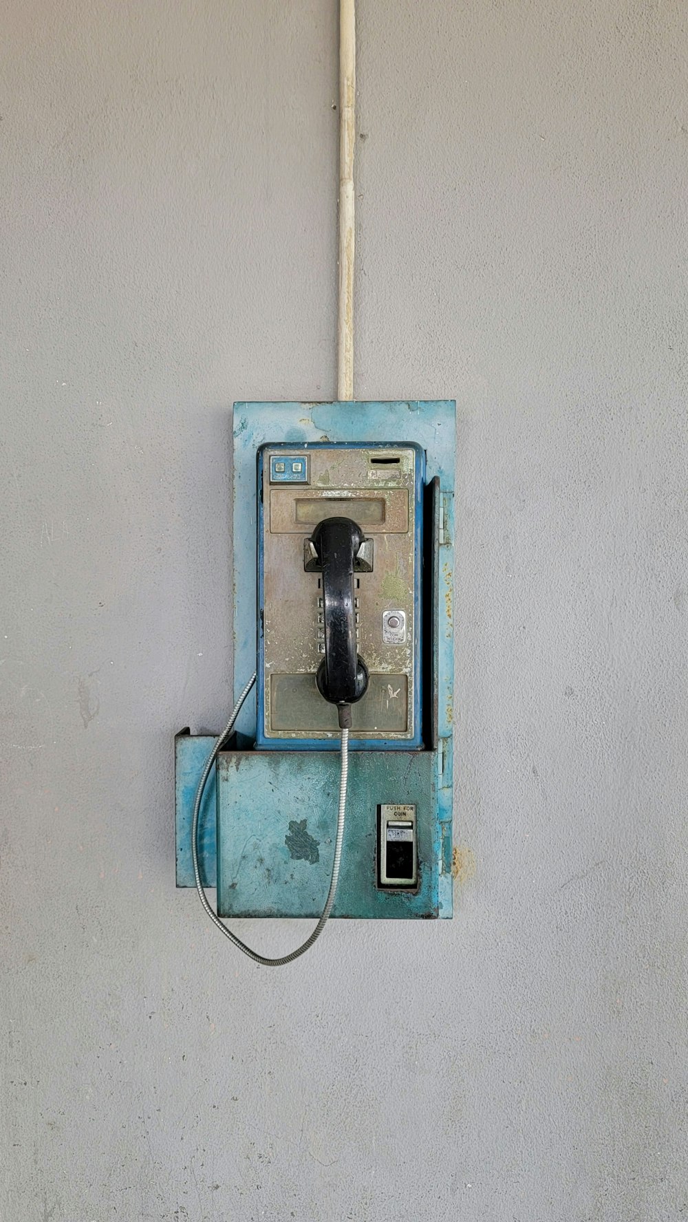 an old phone is hanging on a wall