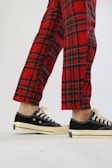 a person in plaid pants and black sneakers