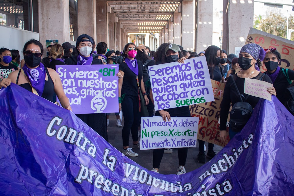 a group of people holding signs and wearing masks