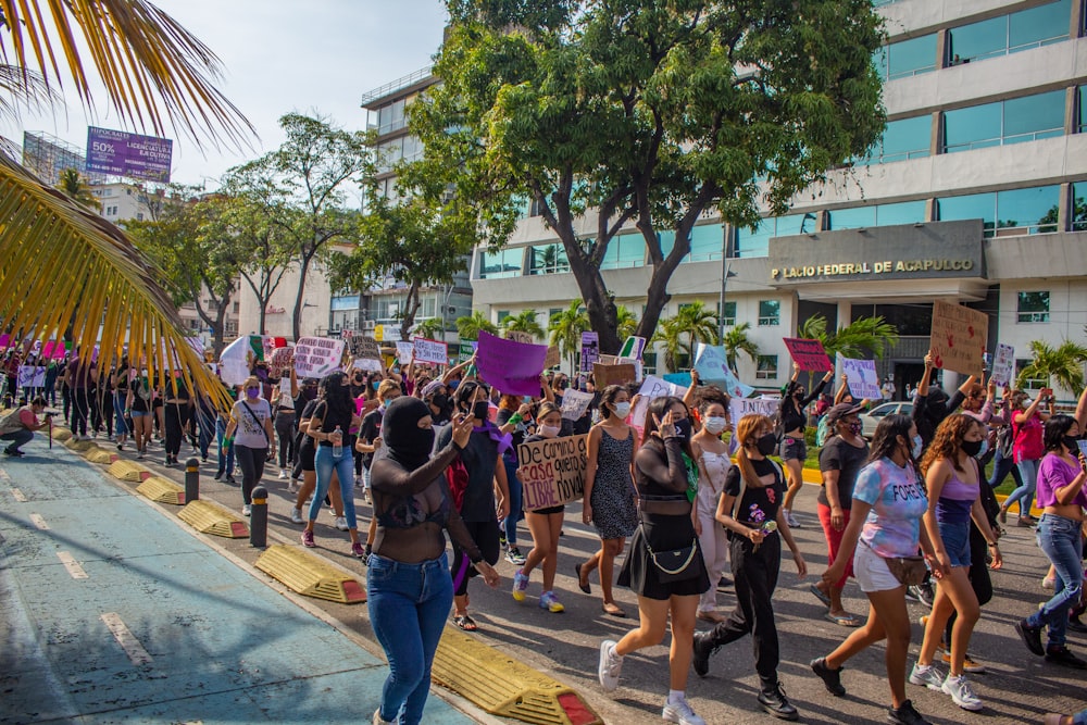 a group of people walking down a street holding signs