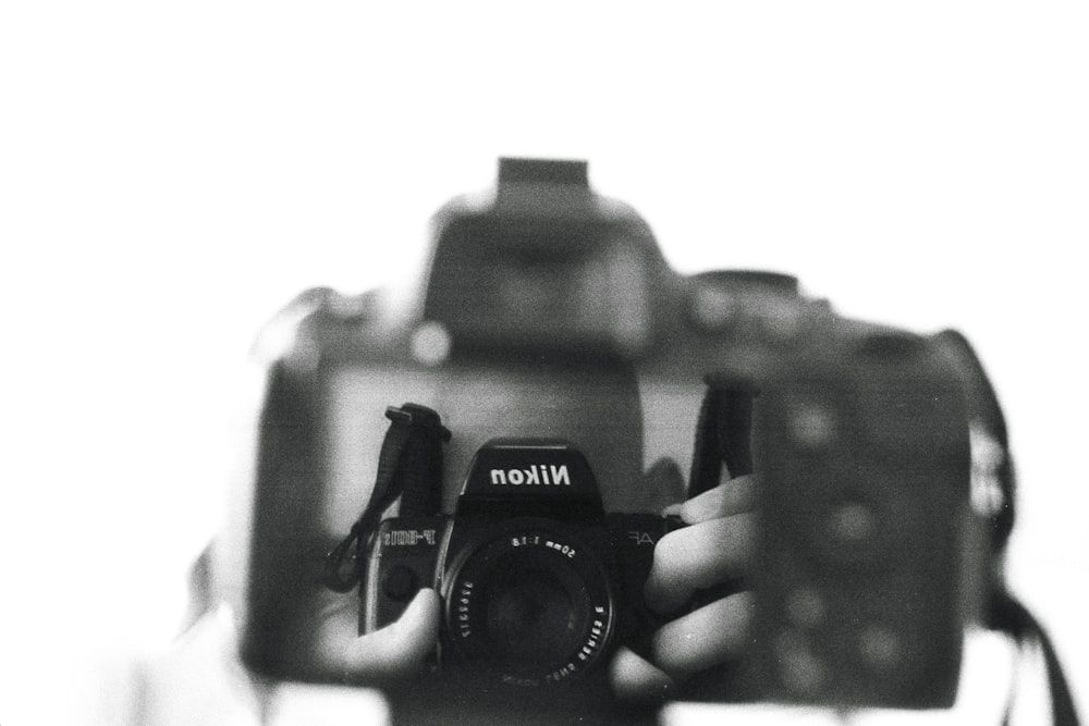 a black and white photo of a person holding a camera