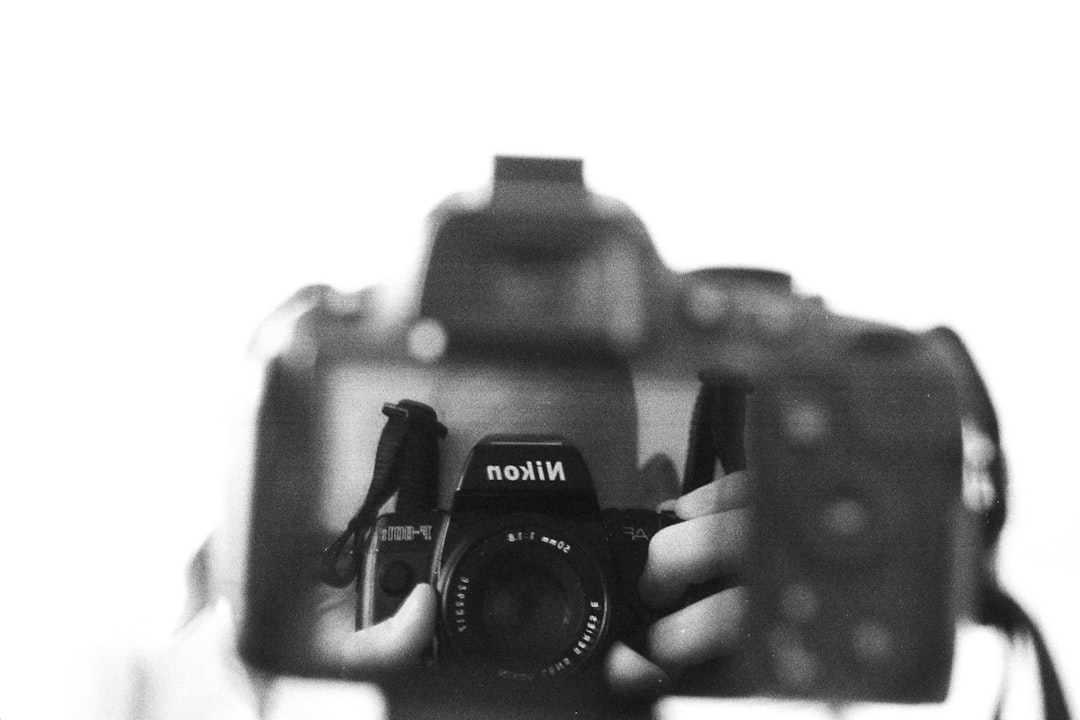 a black and white photo of a person holding a camera,