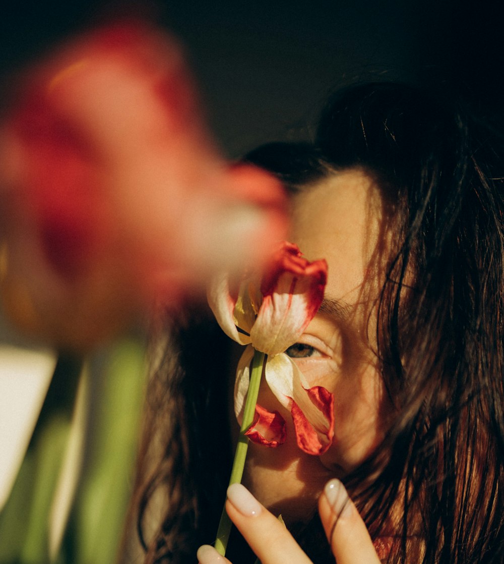 a woman holding a flower in front of her face