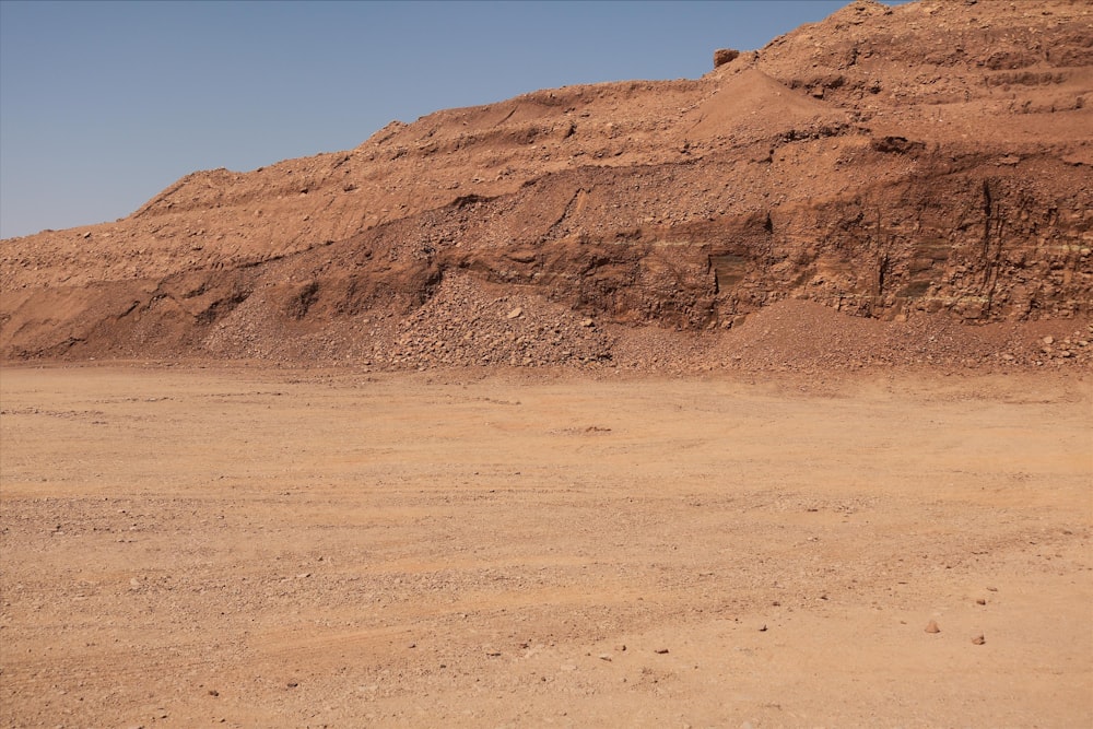 a dirt field with a mountain in the background