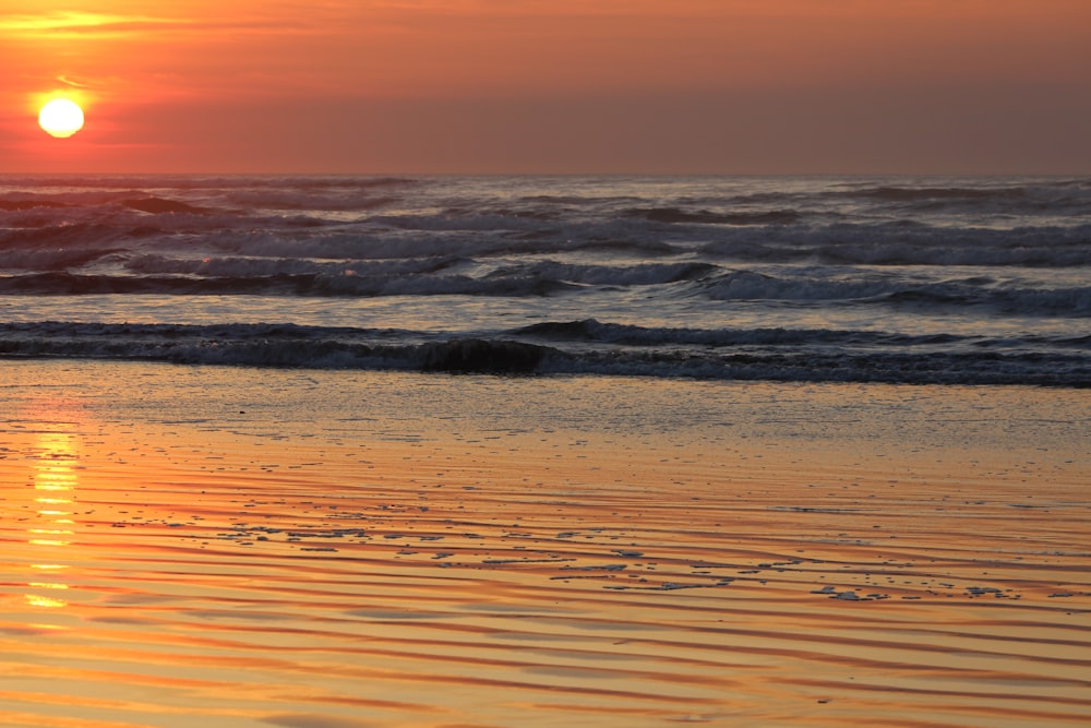 the sun is setting over the ocean with waves